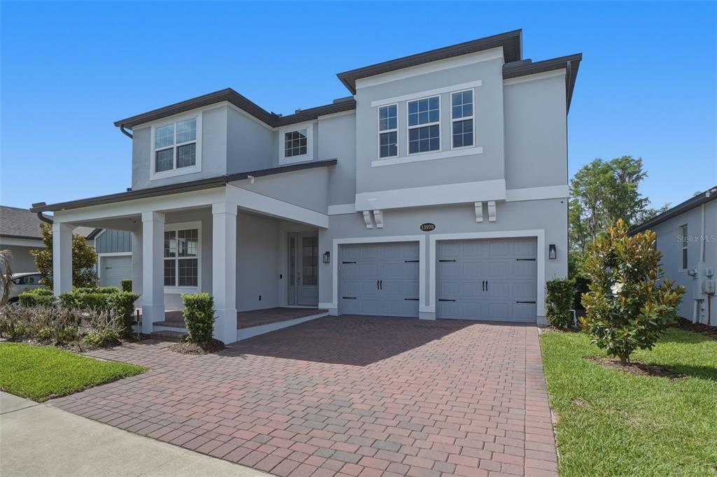 A two-story house with a gray exterior, a brick paver driveway, and a two-car garage — 13978 LANYARD WAY, WINTER GARDEN, FL
