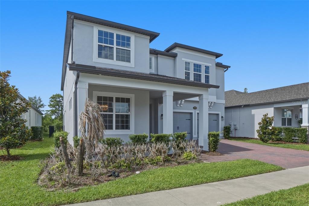 A two-story gray house with a covered front porch and a brick paver driveway — 13978 LANYARD WAY, WINTER GARDEN, FL