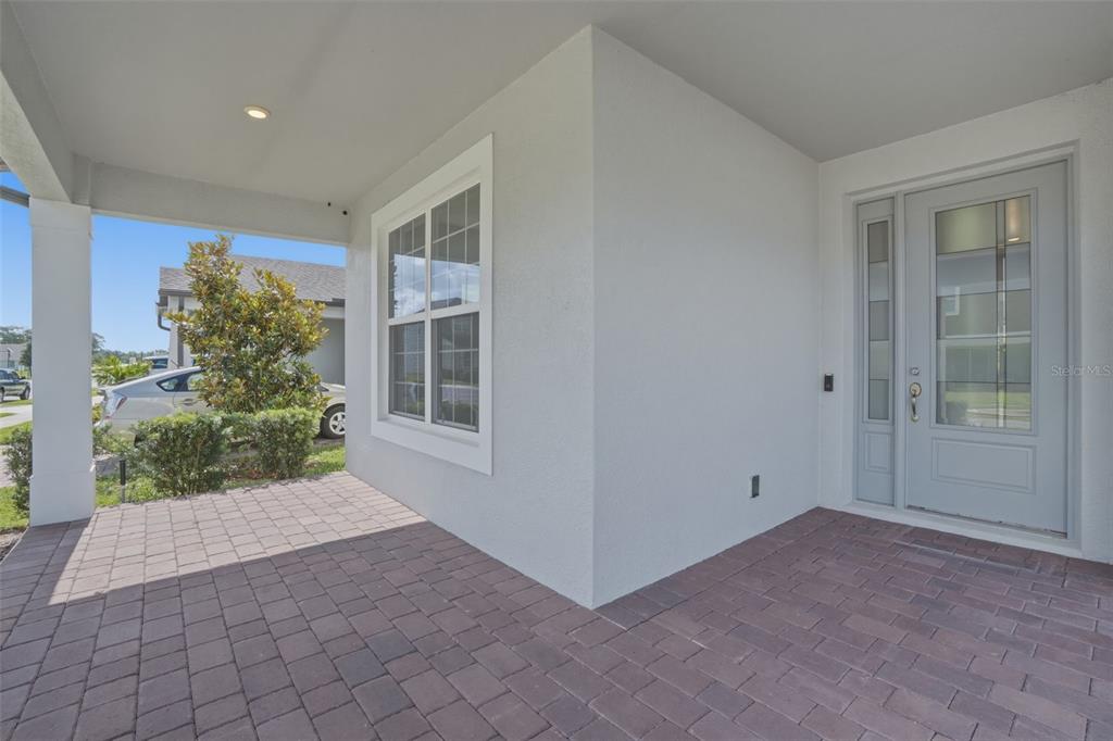 A covered front porch features gray stucco walls, a paved floor, and a glass-paneled door — 13978 LANYARD WAY, WINTER GARDEN, FL