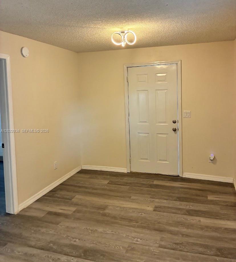 An empty room features light-colored walls, wood-look flooring, a white door, and a ceiling light — 117 NE 5TH ST NE # 113, Winter Haven FL 33881, WINTER HAVEN, FL