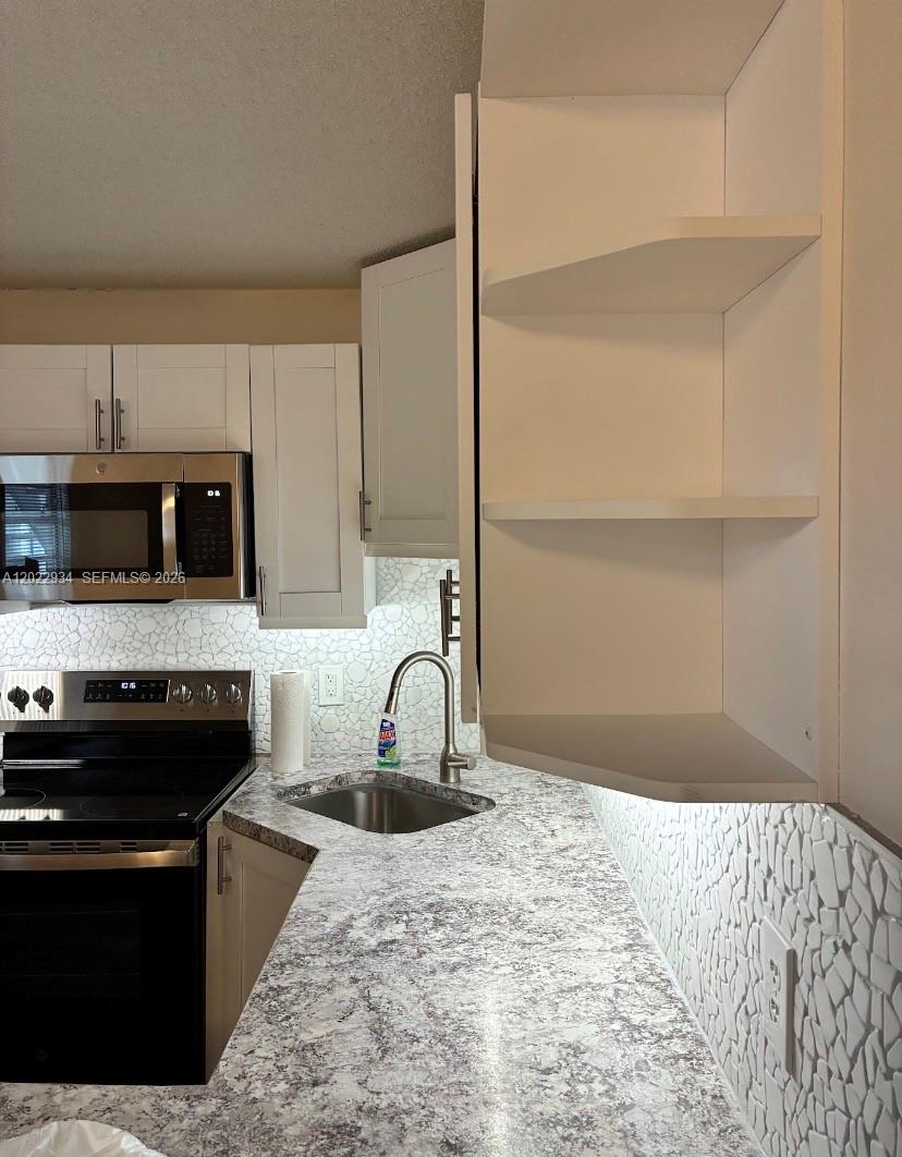 A kitchen features white cabinets, a stainless steel microwave, and a speckled laminate countertop — 117 NE 5TH ST NE # 113, Winter Haven FL 33881, WINTER HAVEN, FL