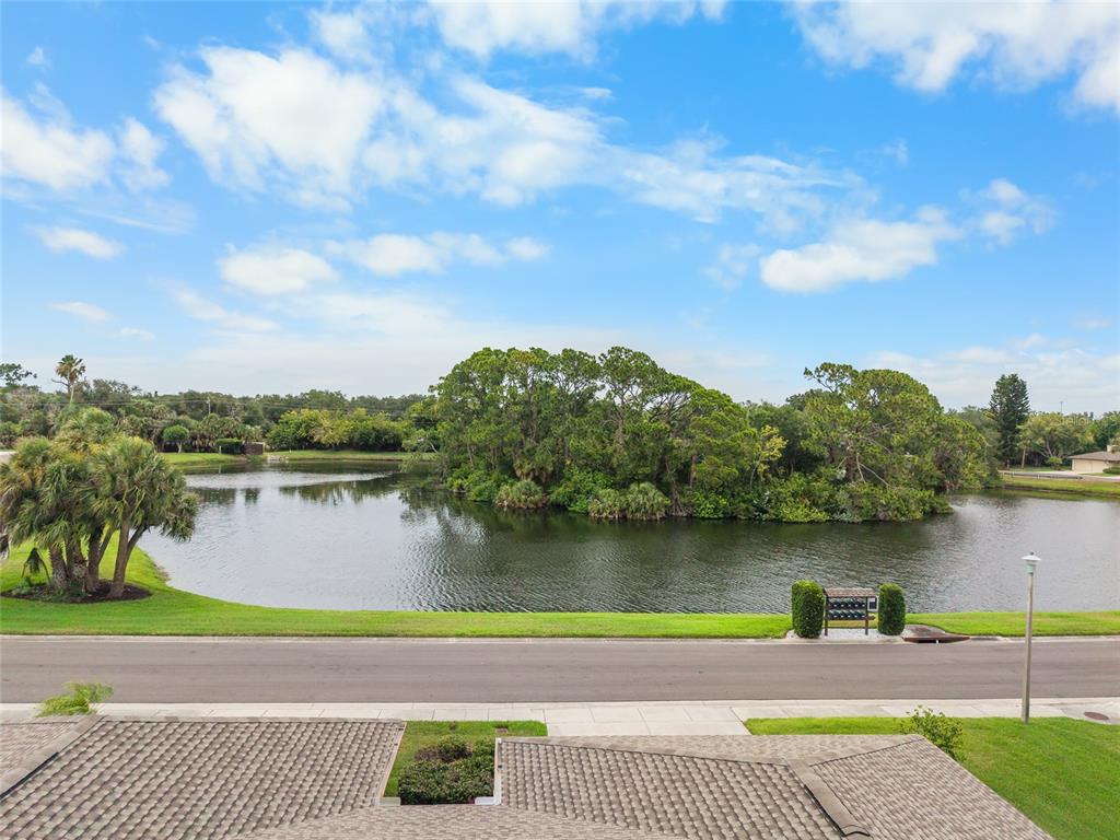 An elevated view shows a road separating a grassy lawn from a pond and trees — 3766 BALLANTRAE DRIVE UNIT 22D, SARASOTA, FL