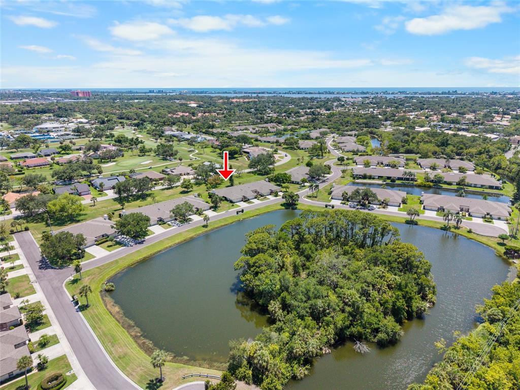 An aerial view shows a residential neighborhood with a pond and a red arrow marker — 3766 BALLANTRAE DRIVE UNIT 22D, SARASOTA, FL