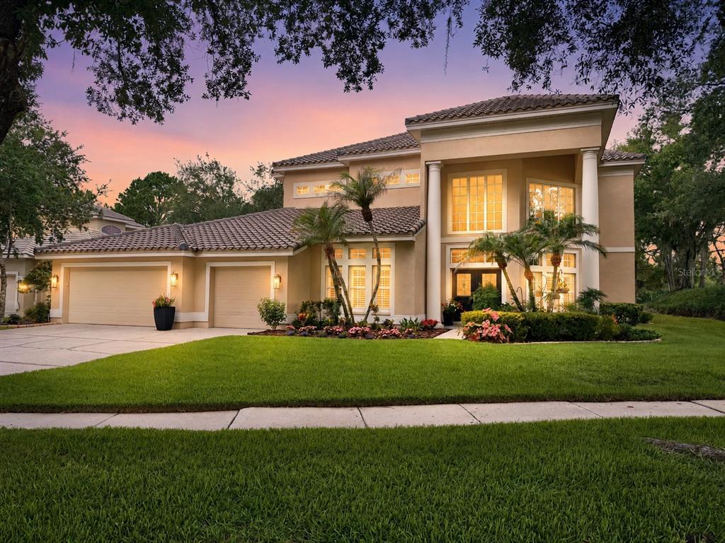 A two-story house with a tan stucco exterior, tile roof, and a three-car garage — 17422 HEATHER OAKS PLACE, TAMPA, FL