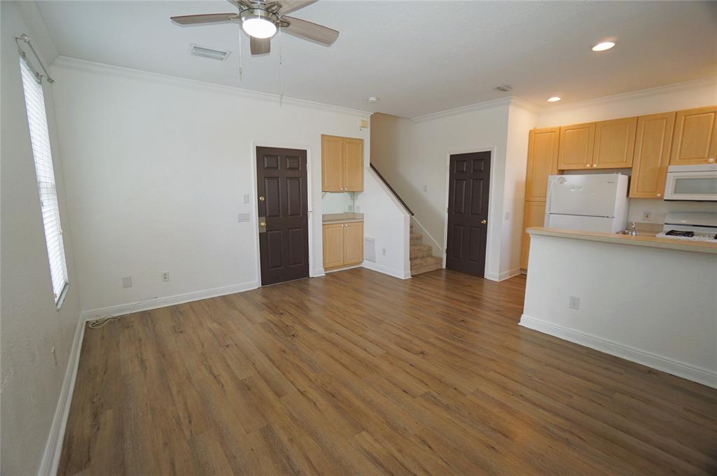 An open-concept living area with wood-look flooring, a kitchen, and a staircase — 101 KEY HAVEN COURT UNIT 1, TAMPA, FL
