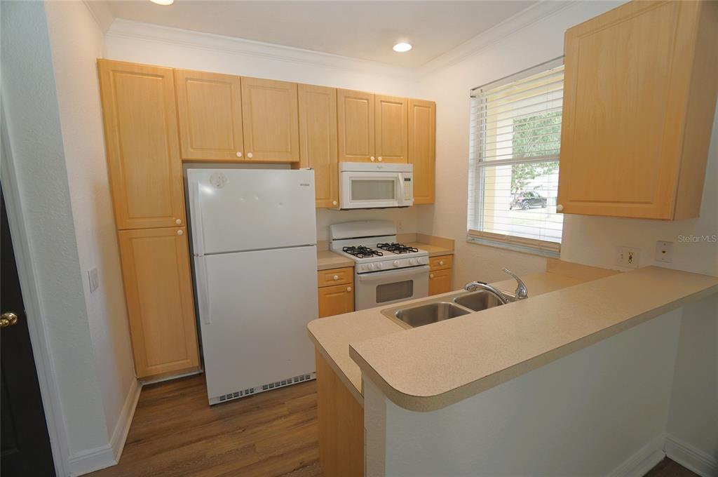 A kitchen with light wood cabinets, white appliances, and a breakfast bar — 101 KEY HAVEN COURT UNIT 1, TAMPA, FL