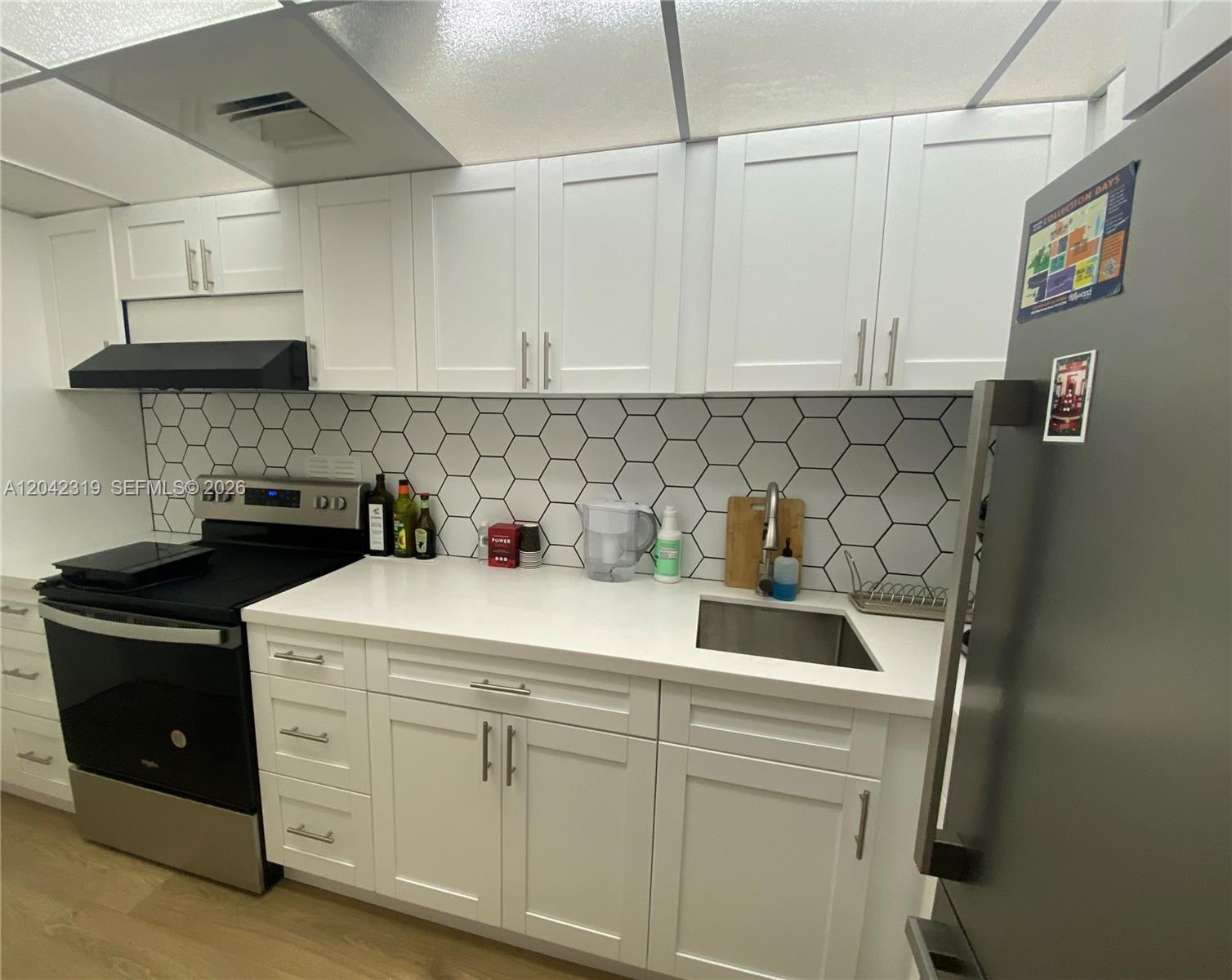 A kitchen features white shaker cabinets, a black stove, and a white hexagonal tile backsplash — 1000 West Avenue # 531, Miami Beach FL 33139, MIAMI BEACH, FL