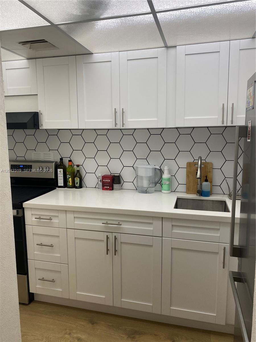 A kitchen features white shaker cabinets, a white countertop, and a hexagonal tile backsplash — 1000 West Avenue # 531, Miami Beach FL 33139, MIAMI BEACH, FL