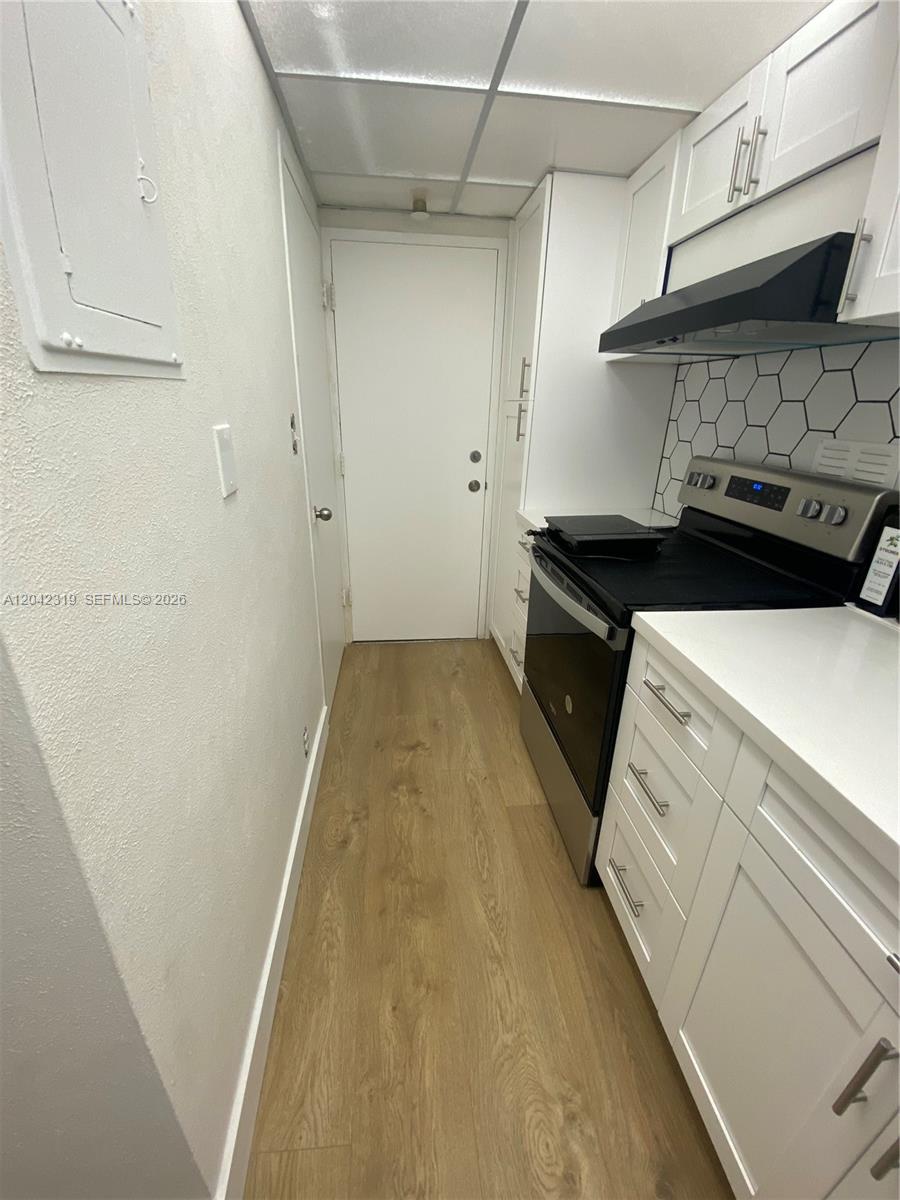 A narrow galley kitchen features white cabinets, stainless steel appliances, and a hexagonal tile backsplash — 1000 West Avenue # 531, Miami Beach FL 33139, MIAMI BEACH, FL