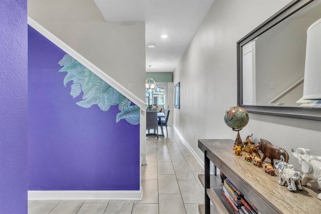A hallway with a purple wall featuring a leaf mural leads to a dining area — 4815 S LOVE STOREY LANE, KISSIMMEE, FL