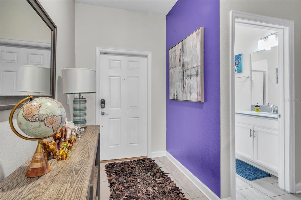 An entryway features a purple accent wall, a globe on a console table, and a bathroom — 4815 S LOVE STOREY LANE, KISSIMMEE, FL