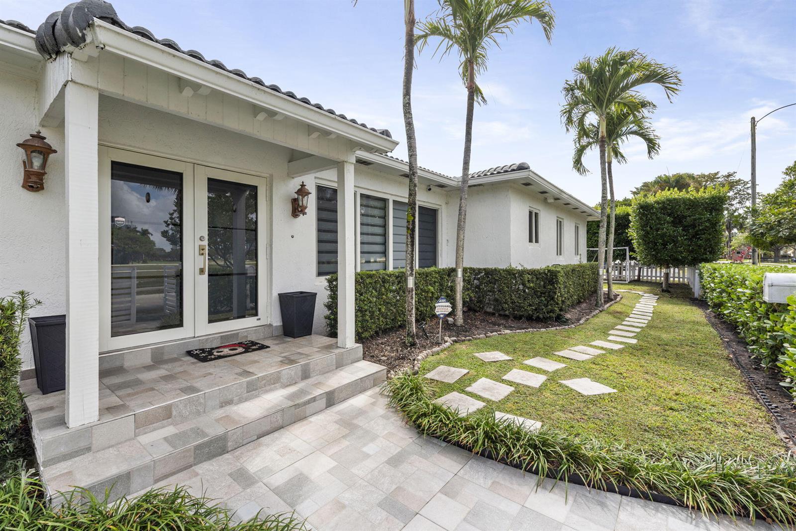 A white house exterior features a tiled entryway, double glass doors, and a stone walkway — 409 N 14th Avenue, Hollywood FL 33020, HOLLYWOOD, FL