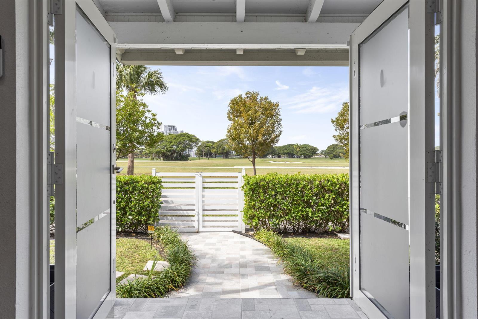 A view through open glass doors shows a stone walkway leading to a white gate — 409 N 14th Avenue, Hollywood FL 33020, HOLLYWOOD, FL