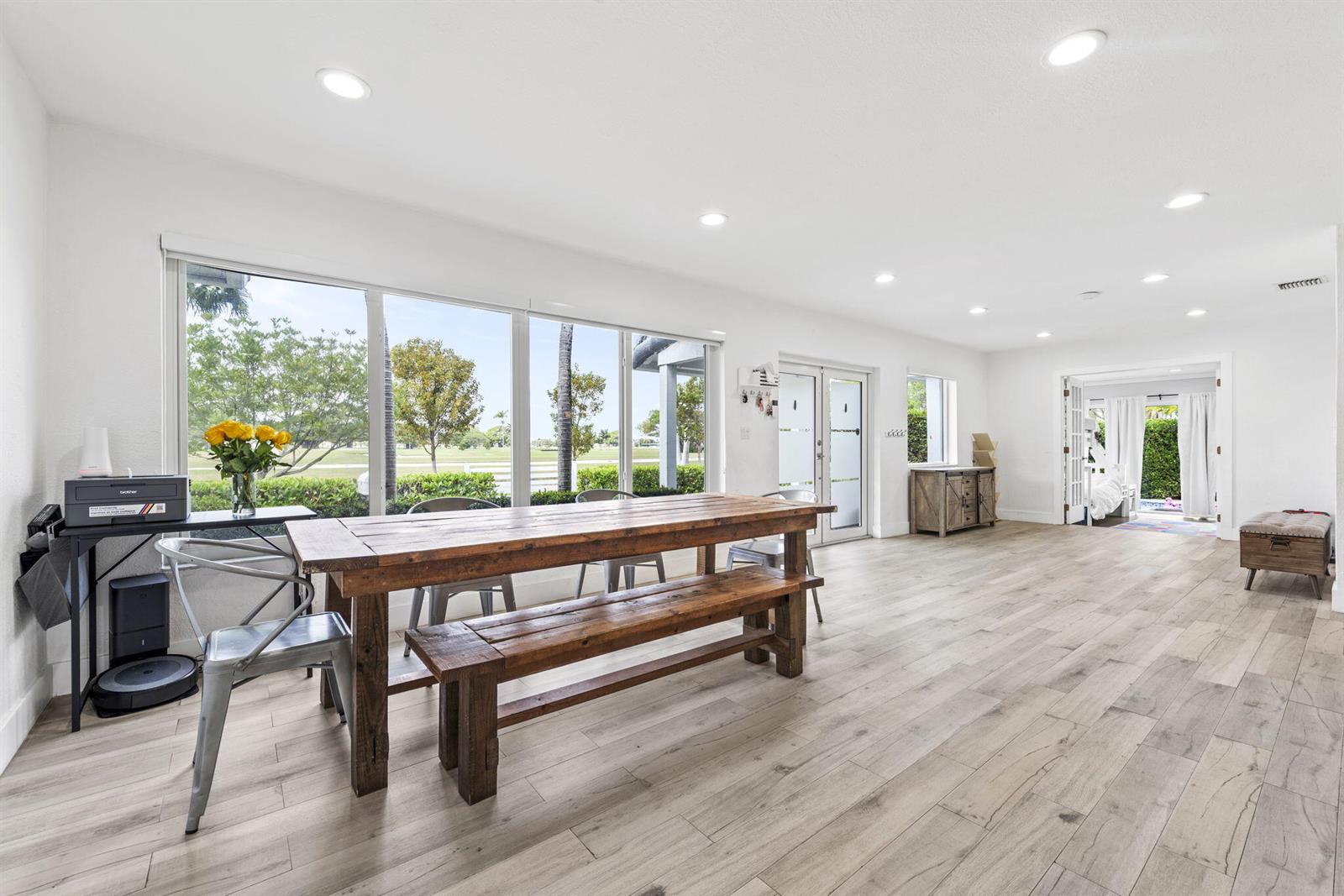 A bright dining area features a rustic wooden table, metal chairs, and light wood flooring — 409 N 14th Avenue, Hollywood FL 33020, HOLLYWOOD, FL