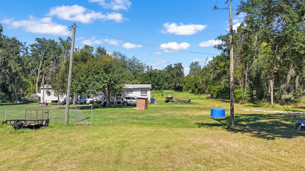 A grassy yard features a mobile home, a utility trailer, and two utility poles — 5606 WATSON ROAD, RIVERVIEW, FL