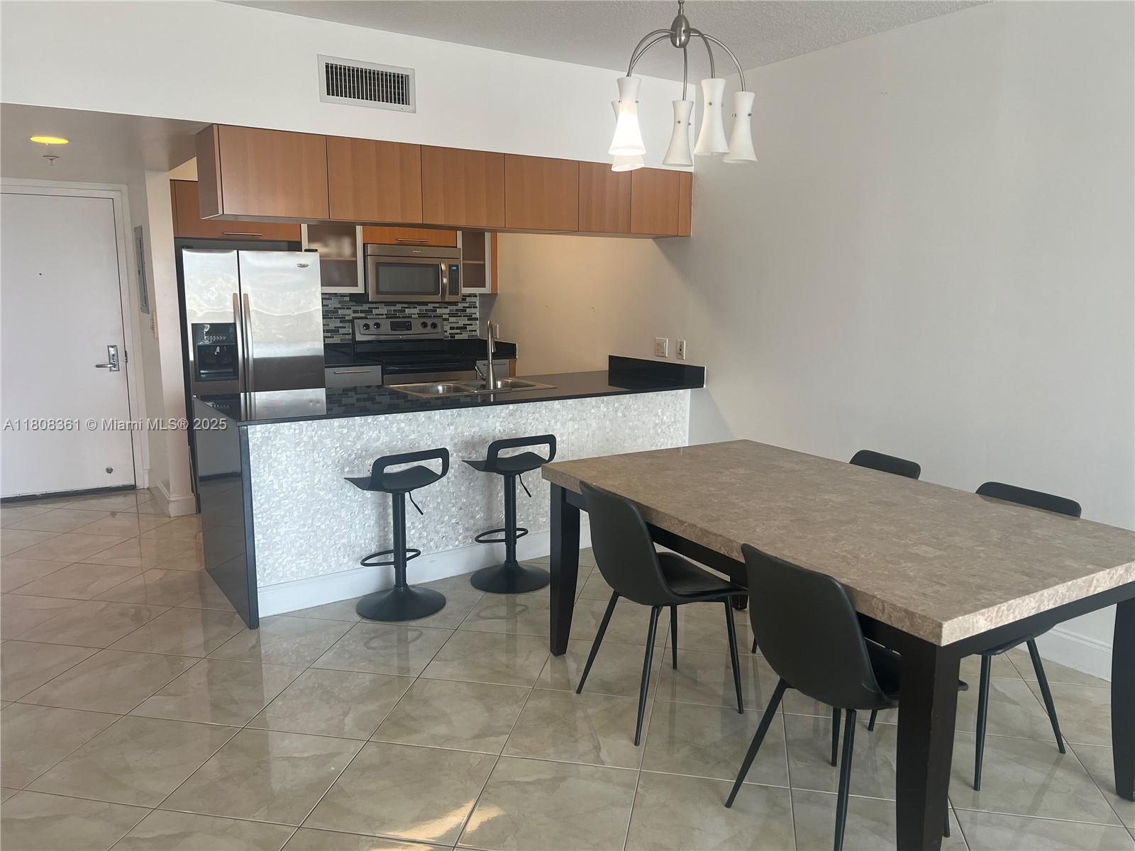 A kitchen with wood cabinets and a breakfast bar overlooks a dining area — 1750 N Bayshore Dr # 1410, Miami FL 33132, MIAMI, FL