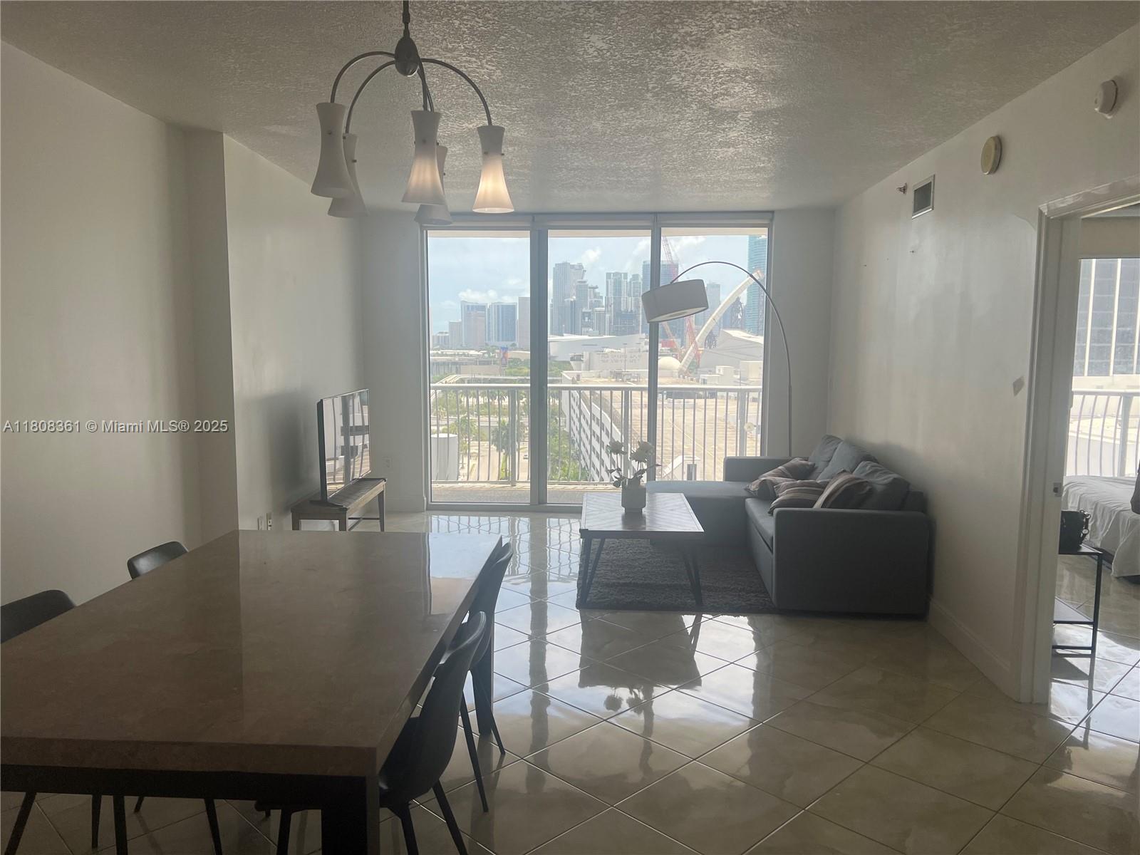 A living and dining area features tile floors, a sectional sofa, and floor-to-ceiling city views — 1750 N Bayshore Dr # 1410, Miami FL 33132, MIAMI, FL