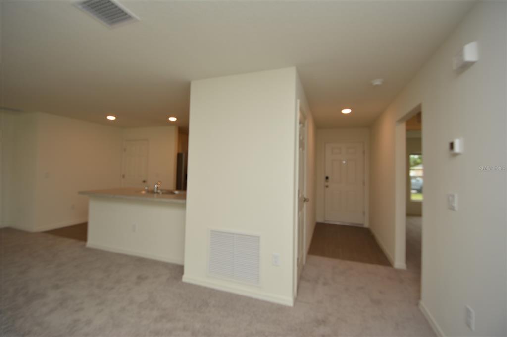 An interior view shows a carpeted living area, a kitchen island, and a front entryway — 38 BALTIMORE LANE, PALM COAST, FL