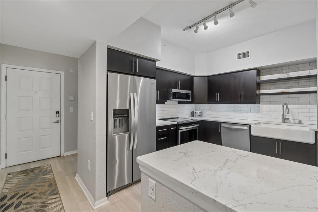 A modern kitchen features dark cabinets, stainless steel appliances, and a white quartz island countertop — 410 S ARMENIA AVENUE UNIT 929A, TAMPA, FL