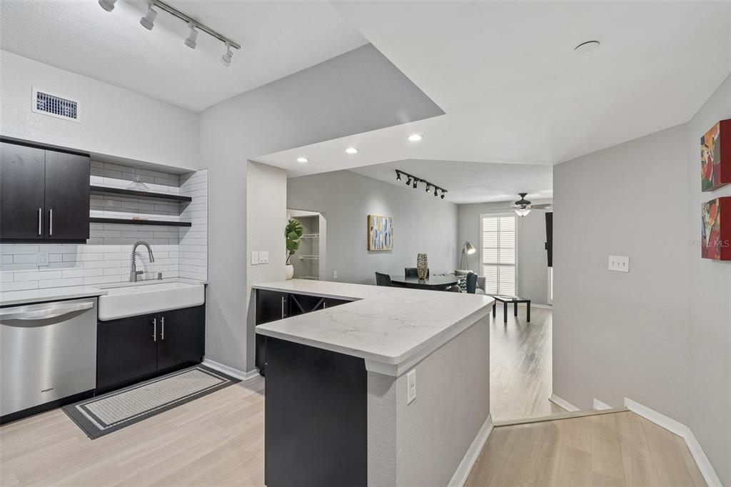 A kitchen with black cabinets, white countertops, and a farmhouse sink overlooks a dining area — 410 S ARMENIA AVENUE UNIT 929A, TAMPA, FL