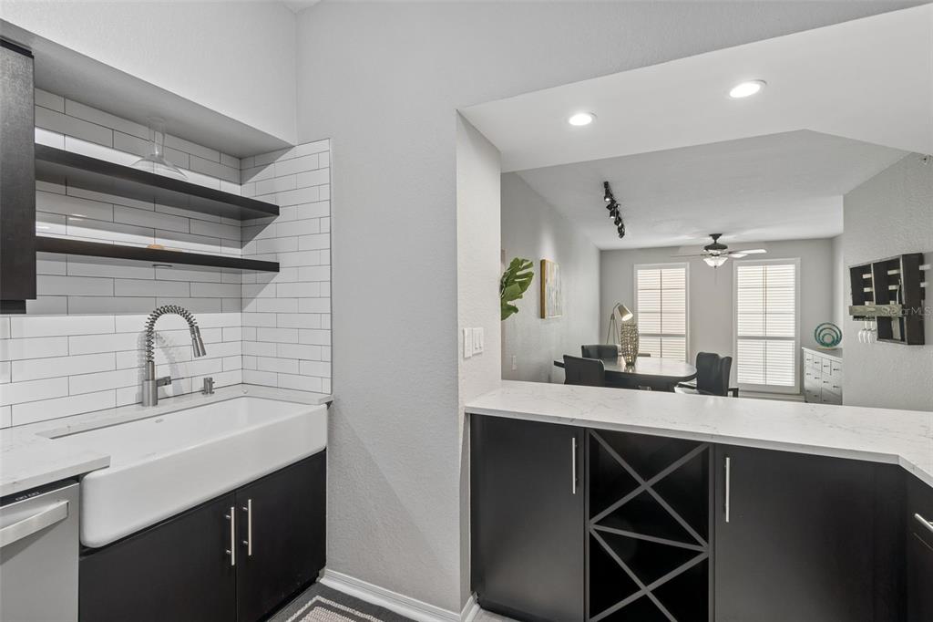 A wet bar with a farmhouse sink, dark cabinets, and white subway tile backsplash — 410 S ARMENIA AVENUE UNIT 929A, TAMPA, FL