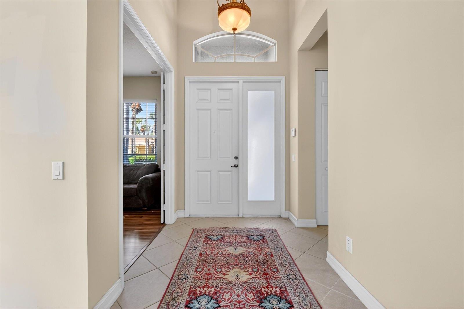 A tiled entryway features a front door with a sidelight, a transom window, and a rug — 7420 Twin Falls Drive, Boynton Beach FL 33437, BOYNTON BEACH, FL