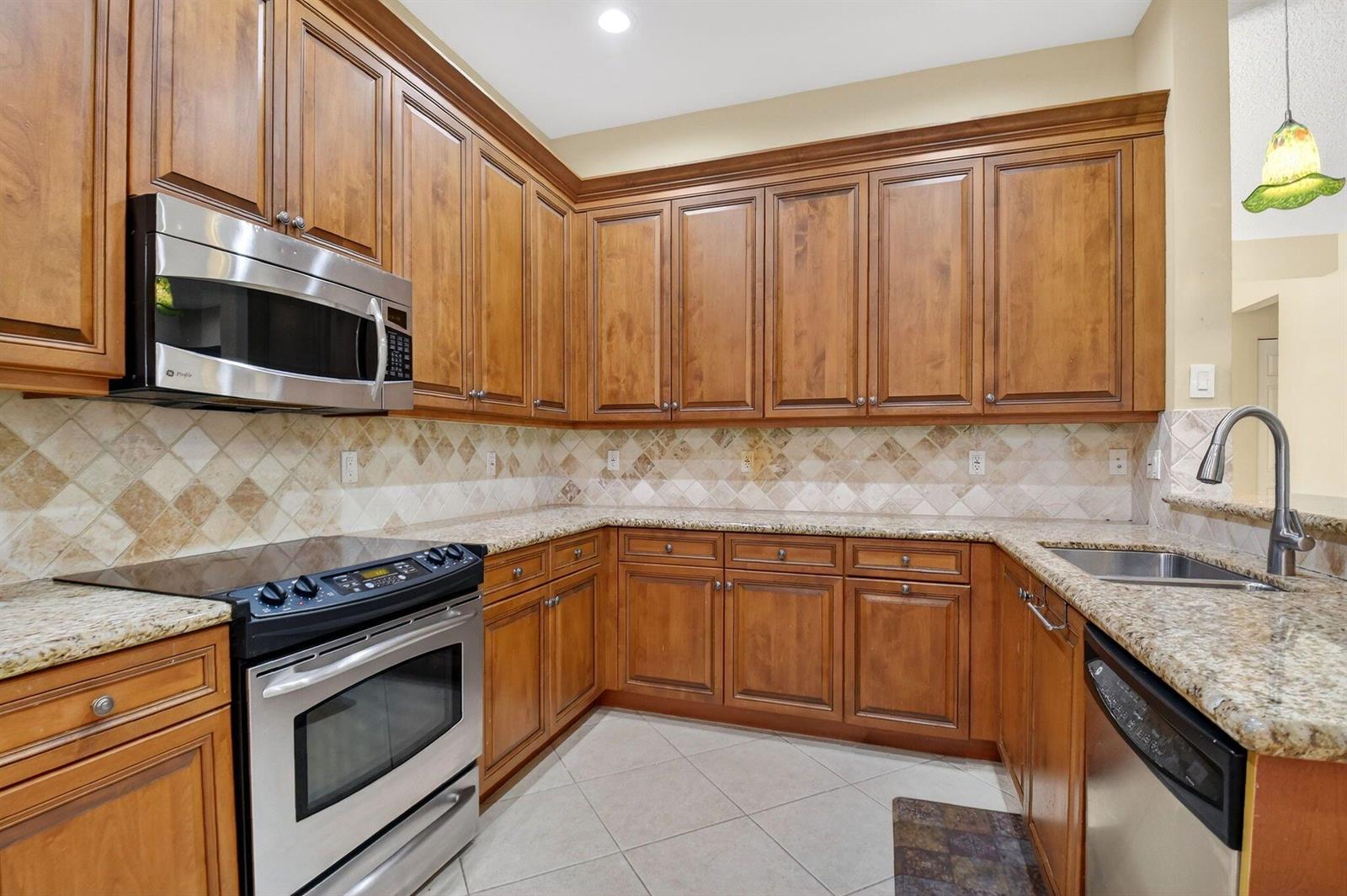 A kitchen with wood cabinets, granite countertops, stainless steel appliances, and a tiled backsplash — 7420 Twin Falls Drive, Boynton Beach FL 33437, BOYNTON BEACH, FL