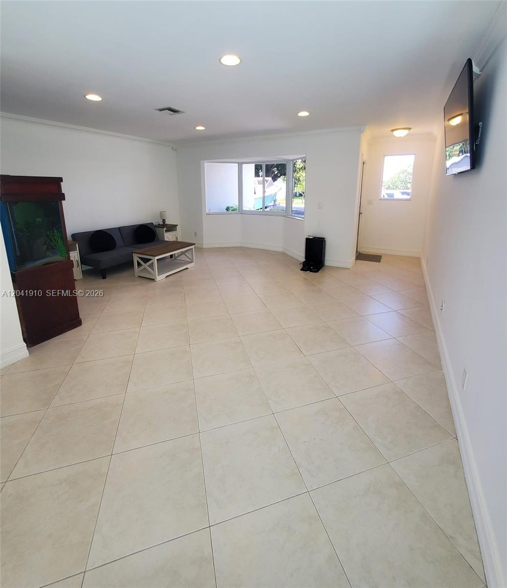 A living room features white walls, tile flooring, a sofa, a coffee table, and an aquarium — 1800 N 55th Ave, Hollywood FL 33021, HOLLYWOOD, FL