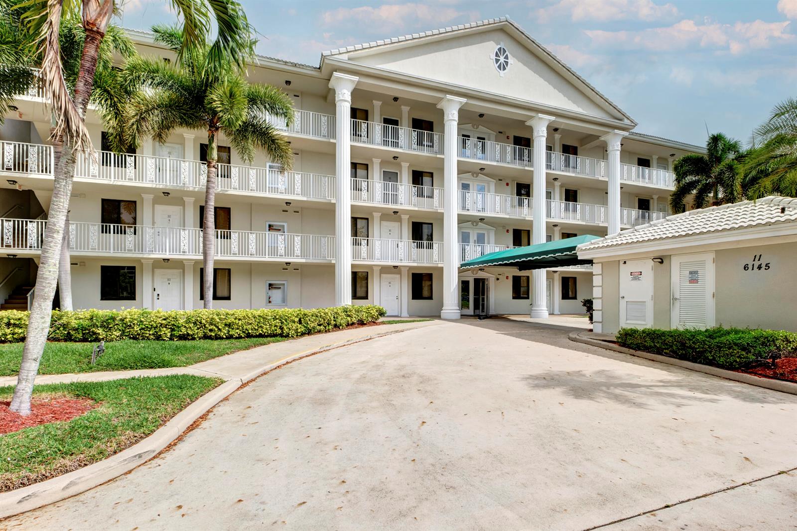 A multi-story apartment building features white columns, balconies, and a green covered entrance — 6145 Balboa Circle # 103, Boca Raton FL 33433, BOCA RATON, FL