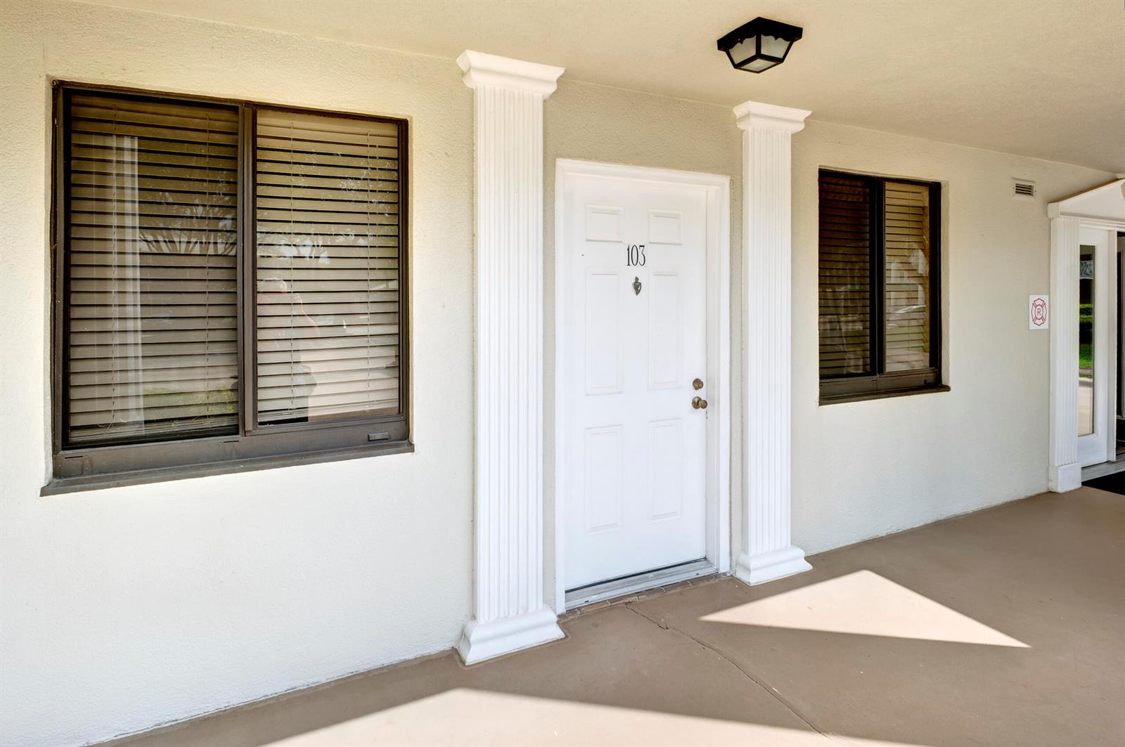 An exterior view of a building entrance with a white door numbered 103 — 6145 Balboa Circle # 103, Boca Raton FL 33433, BOCA RATON, FL