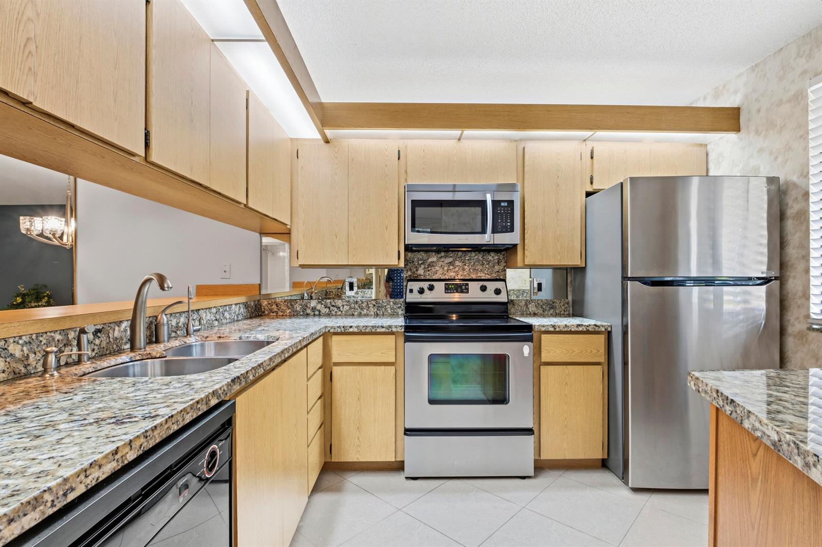A kitchen features light wood cabinets, granite countertops, and stainless steel appliances — 6145 Balboa Circle # 103, Boca Raton FL 33433, BOCA RATON, FL