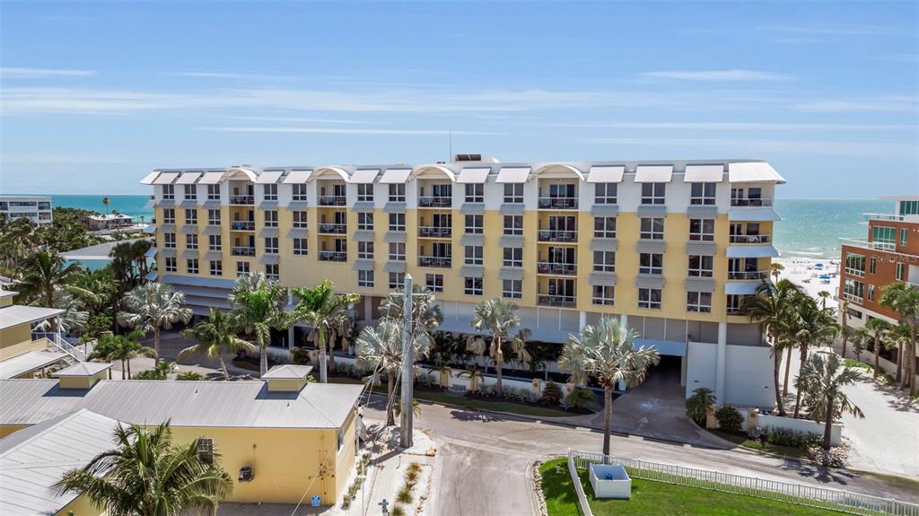 An exterior view of a multi-story yellow beachfront hotel with balconies and palm trees — 915 SEASIDE DRIVE UNIT 611, SARASOTA, FL