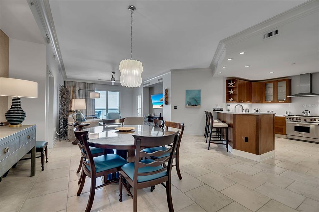 A dining area with a round table and chairs opens into a kitchen with wood cabinetry — 915 SEASIDE DRIVE UNIT 611, SARASOTA, FL
