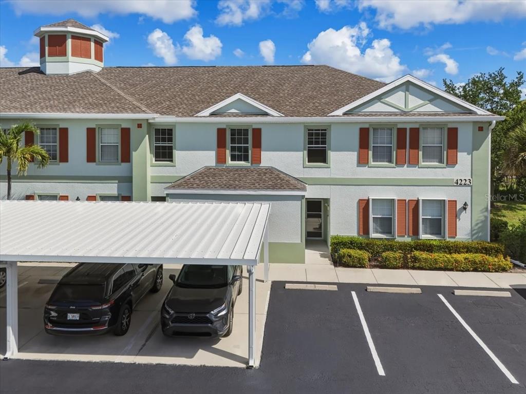 A two-story apartment building exterior features a covered parking area with two parked cars — 4223 LIRON AVENUE UNIT 104, FORT MYERS, FL