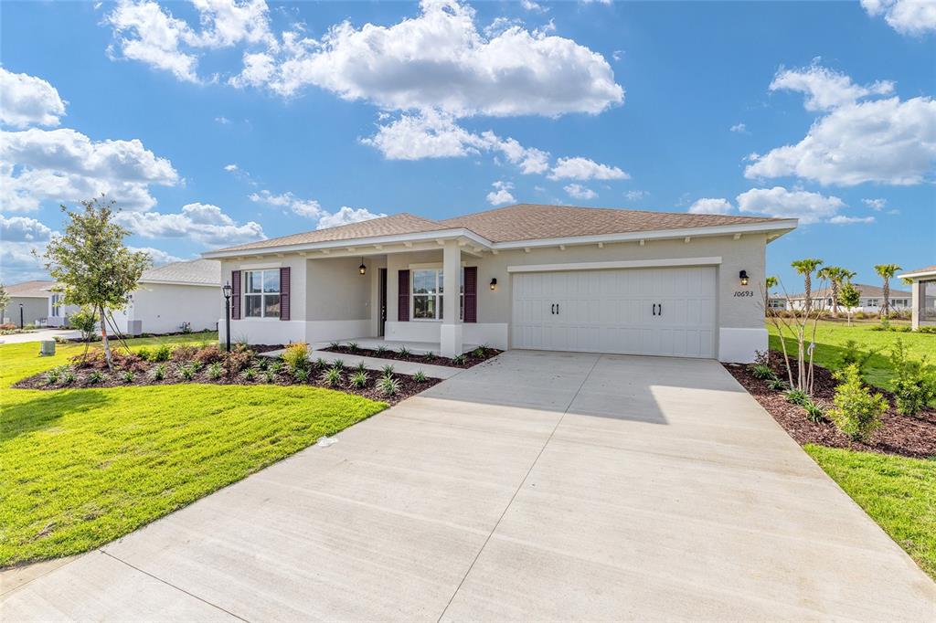 A single-story house with a beige exterior, a two-car garage, and a concrete driveway — 10693 SW 102ND LANE, OCALA, FL