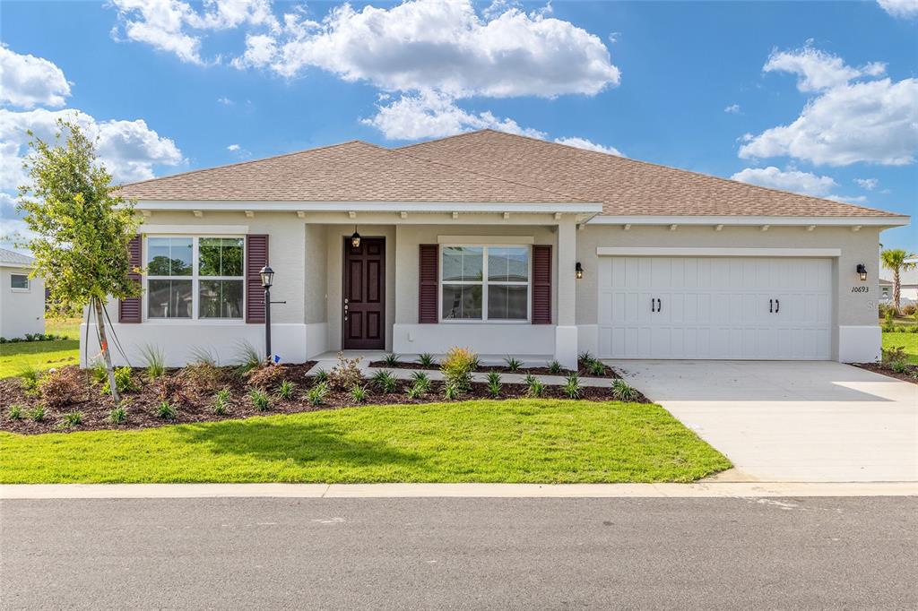 A single-story house with a tan exterior, brown shutters, and a two-car garage — 10693 SW 102ND LANE, OCALA, FL