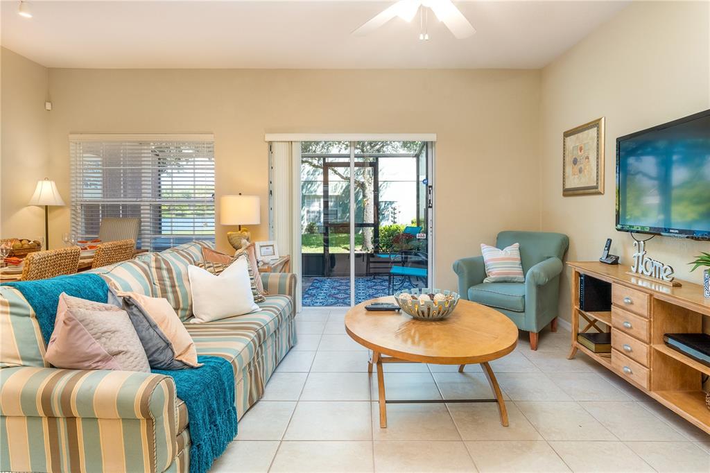 A living room features a striped sofa, a teal armchair, a wooden coffee table, and patio doors — 2457 CARAVELLE CIRCLE, KISSIMMEE, FL
