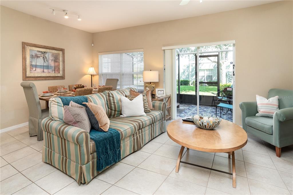 A living room with a striped sofa, round wooden coffee table, and sliding glass patio doors — 2457 CARAVELLE CIRCLE, KISSIMMEE, FL
