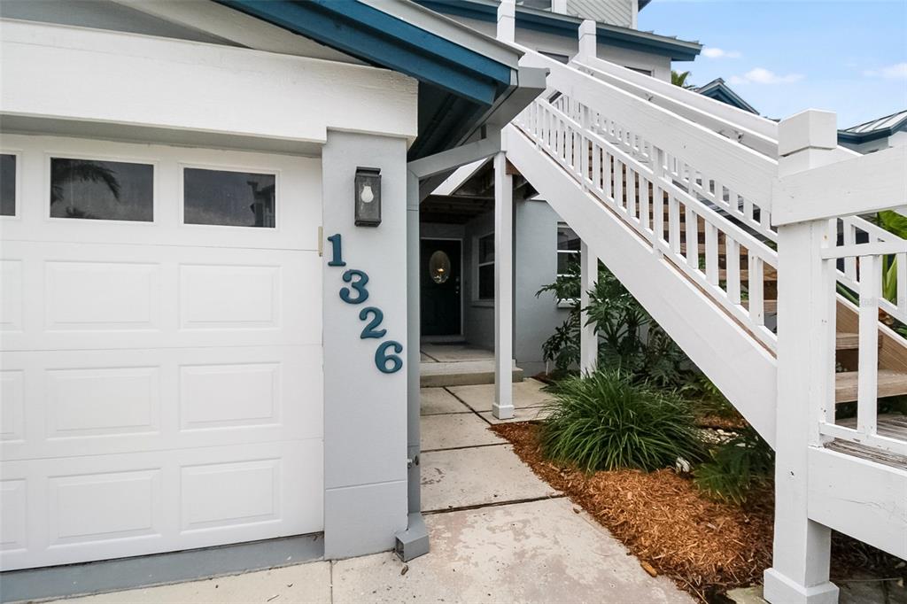 A white garage door, house numbers, and an outdoor staircase lead to a front entrance — 1326 SIESTA BAYSIDE DRIVE UNIT 1326-D, SARASOTA, FL