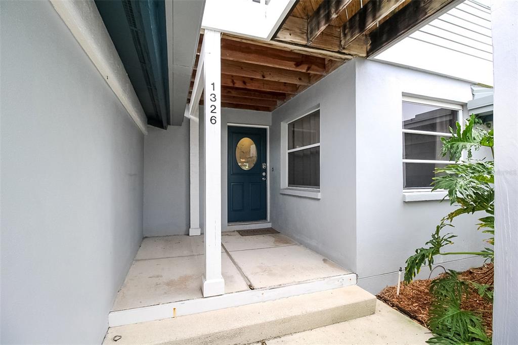 A covered entryway features a blue front door, a white support post, and concrete steps — 1326 SIESTA BAYSIDE DRIVE UNIT 1326-D, SARASOTA, FL