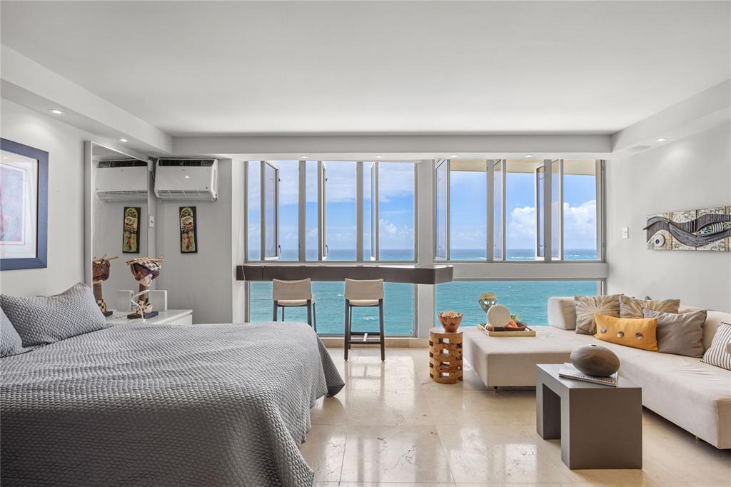 A bedroom and living area with a large window overlooking the ocean and marble floors — 1035 ASHFORD AVENUE UNIT 1206, SAN JUAN, PR