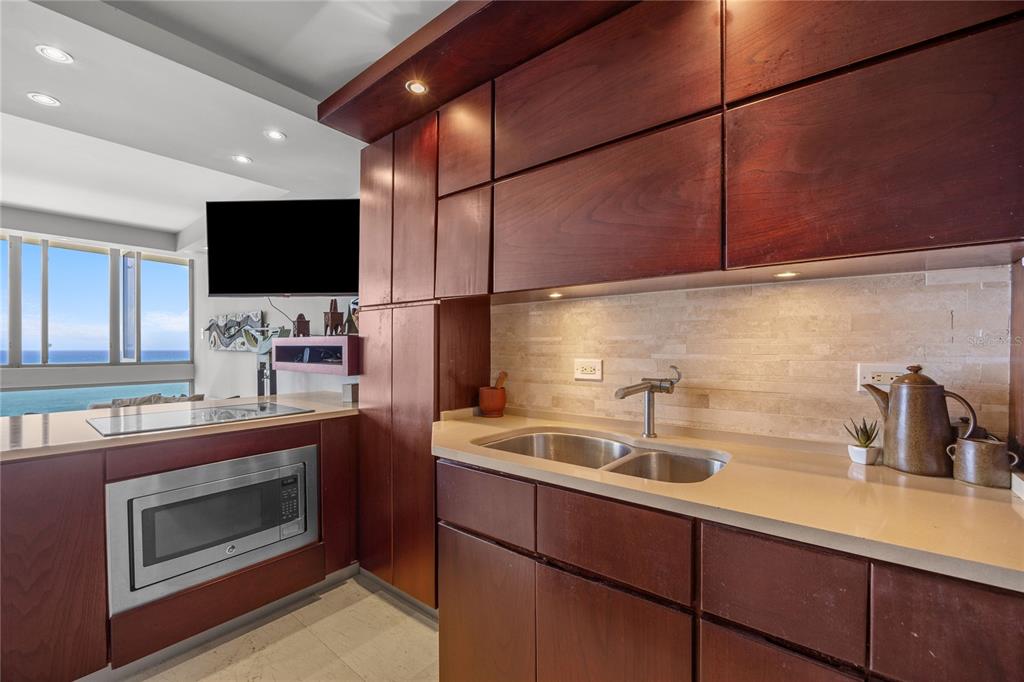 A kitchen with dark wood cabinets, a double sink, and a view of the ocean — 1035 ASHFORD AVENUE UNIT 1206, SAN JUAN, PR