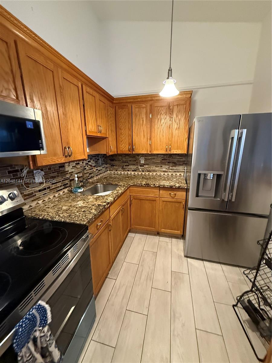 A kitchen features wood cabinets, granite countertops, stainless steel appliances, and light-colored tile flooring — 468 NE 206th Ln # 203, Miami FL 33179, MIAMI, FL