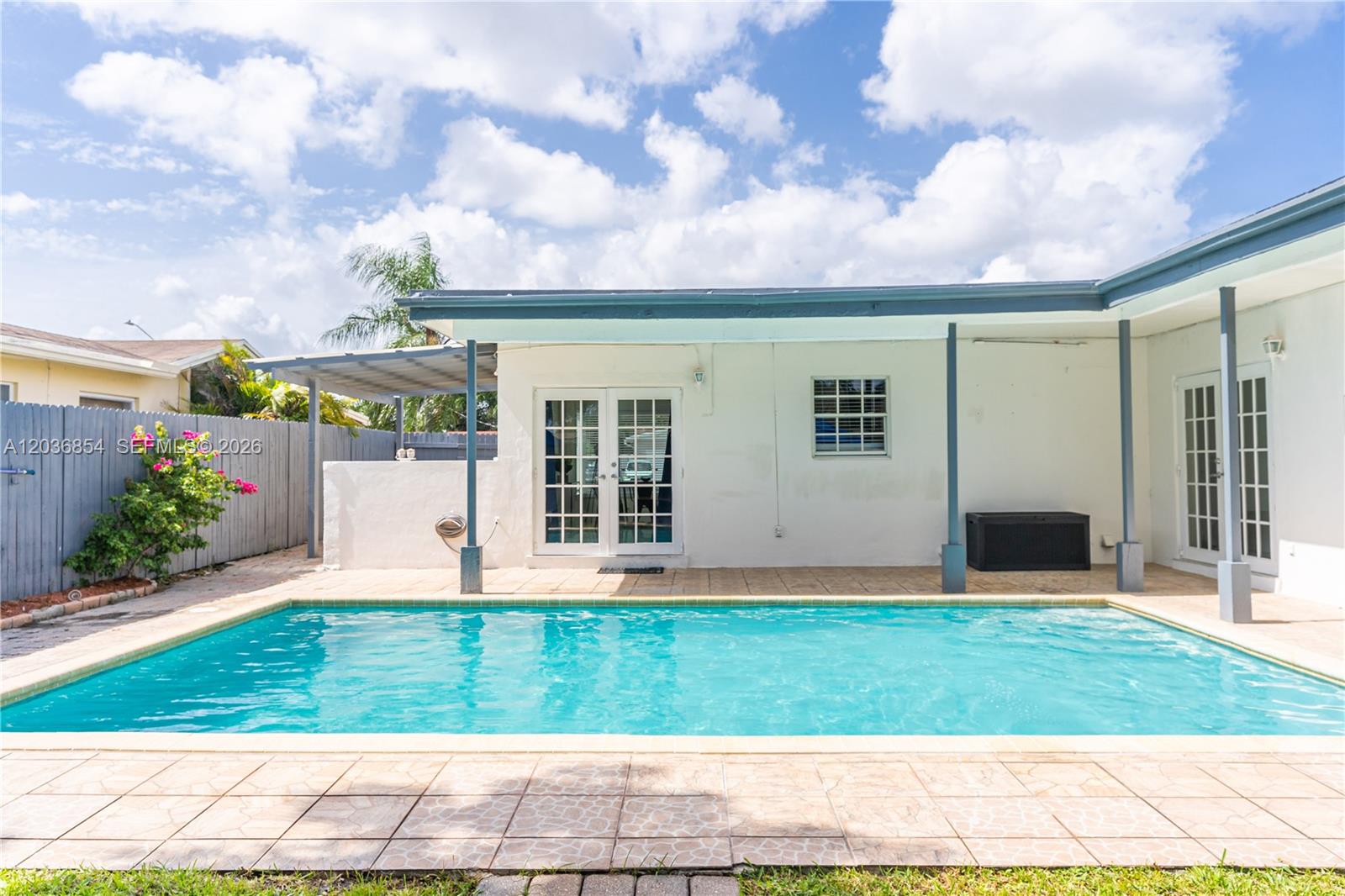 A backyard features a rectangular swimming pool, a covered patio, and a white house exterior — 6452 Custer St, Hollywood FL 33024, HOLLYWOOD, FL