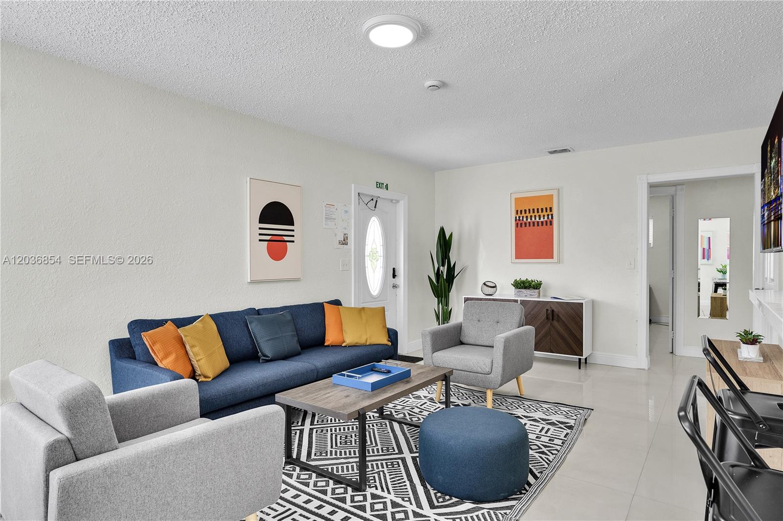 A living room features a blue sofa, two gray armchairs, and a patterned area rug — 6452 Custer St, Hollywood FL 33024, HOLLYWOOD, FL