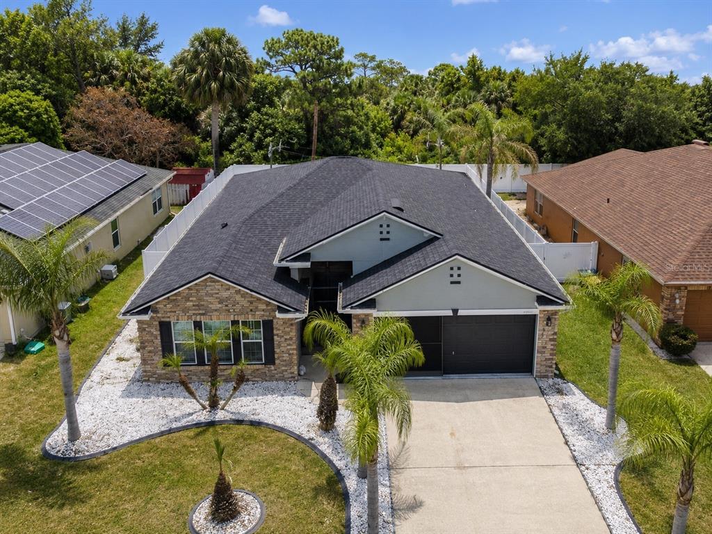 An aerial view of a single-story house with a stone facade, dark roof, and driveway — 2221 PARIA LANE, KISSIMMEE, FL