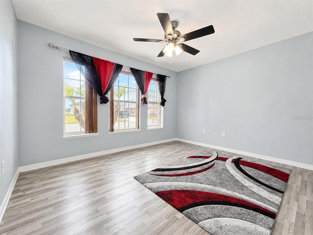 An empty room with light gray walls, wood-look flooring, a ceiling fan, and a patterned rug — 2221 PARIA LANE, KISSIMMEE, FL