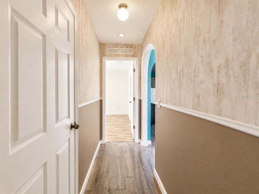 A hallway features wood-look flooring, two-tone walls with chair rail molding, and an arched entryway — 2221 PARIA LANE, KISSIMMEE, FL