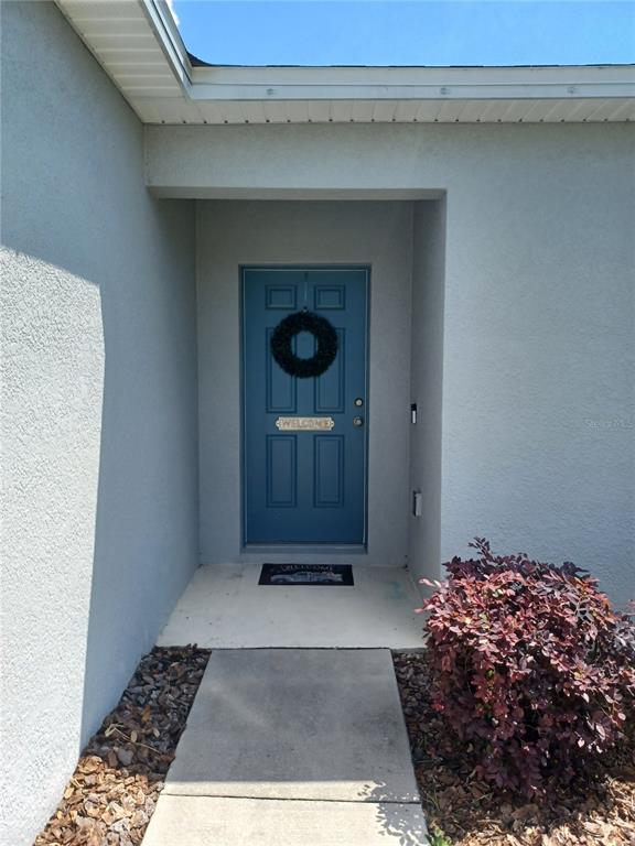A blue front door with a wreath is set within a recessed entryway — 14305 HIDDEN COURT, CLERMONT, FL