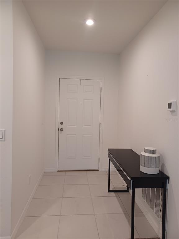 A white-walled entryway features a front door, tiled flooring, and a black console table — 14305 HIDDEN COURT, CLERMONT, FL
